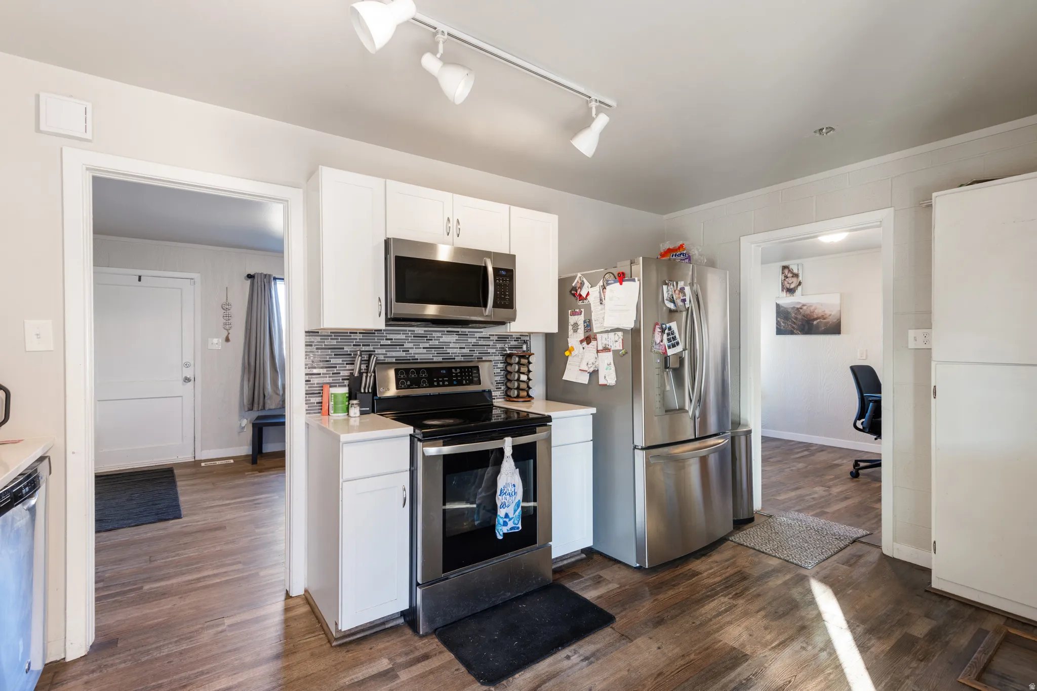 Kitchen featuring white cabinetry, stainless steel appliances, and dark wood-style floors