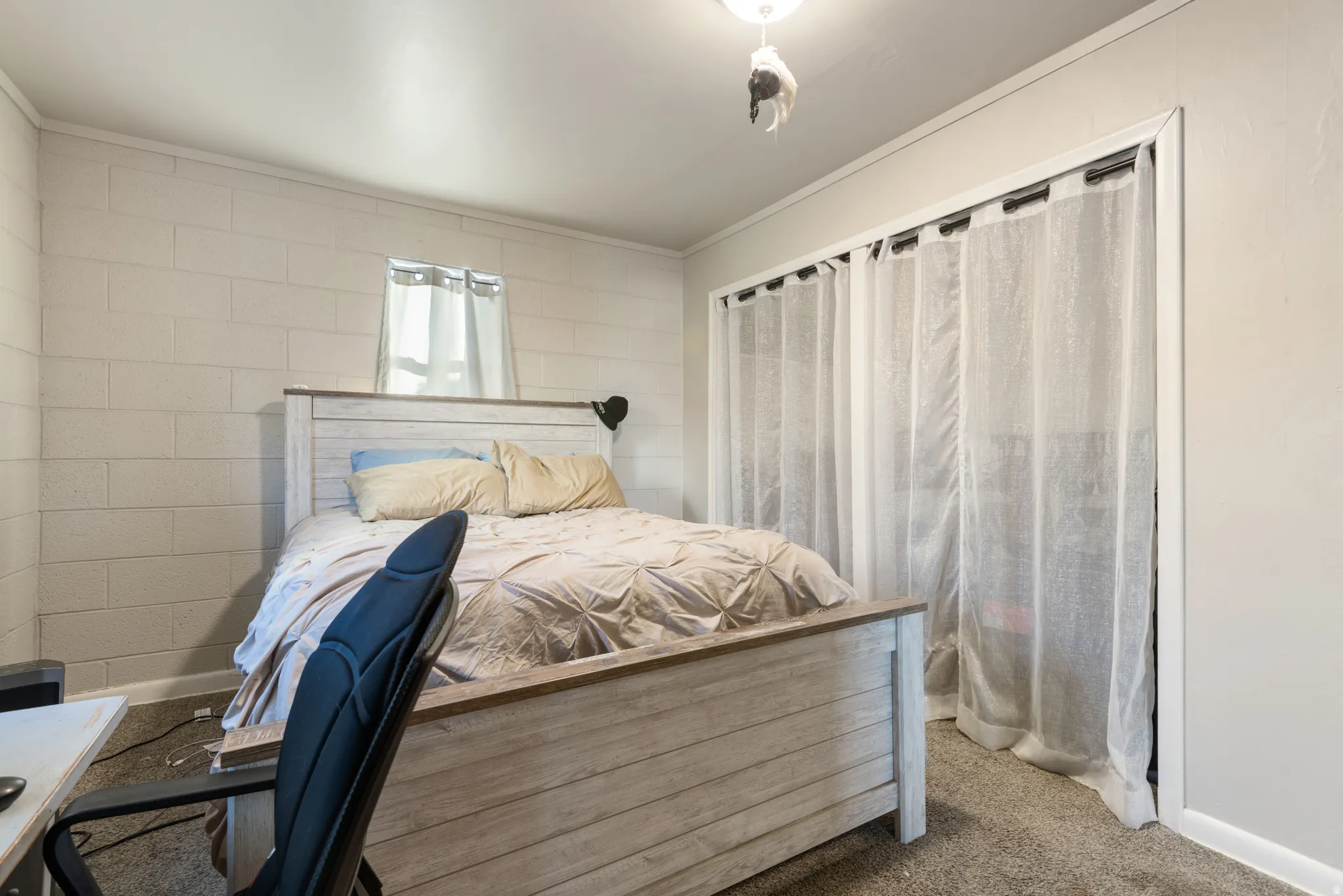 Primary Bedroom with carpet, ornamental molding, and concrete block wall