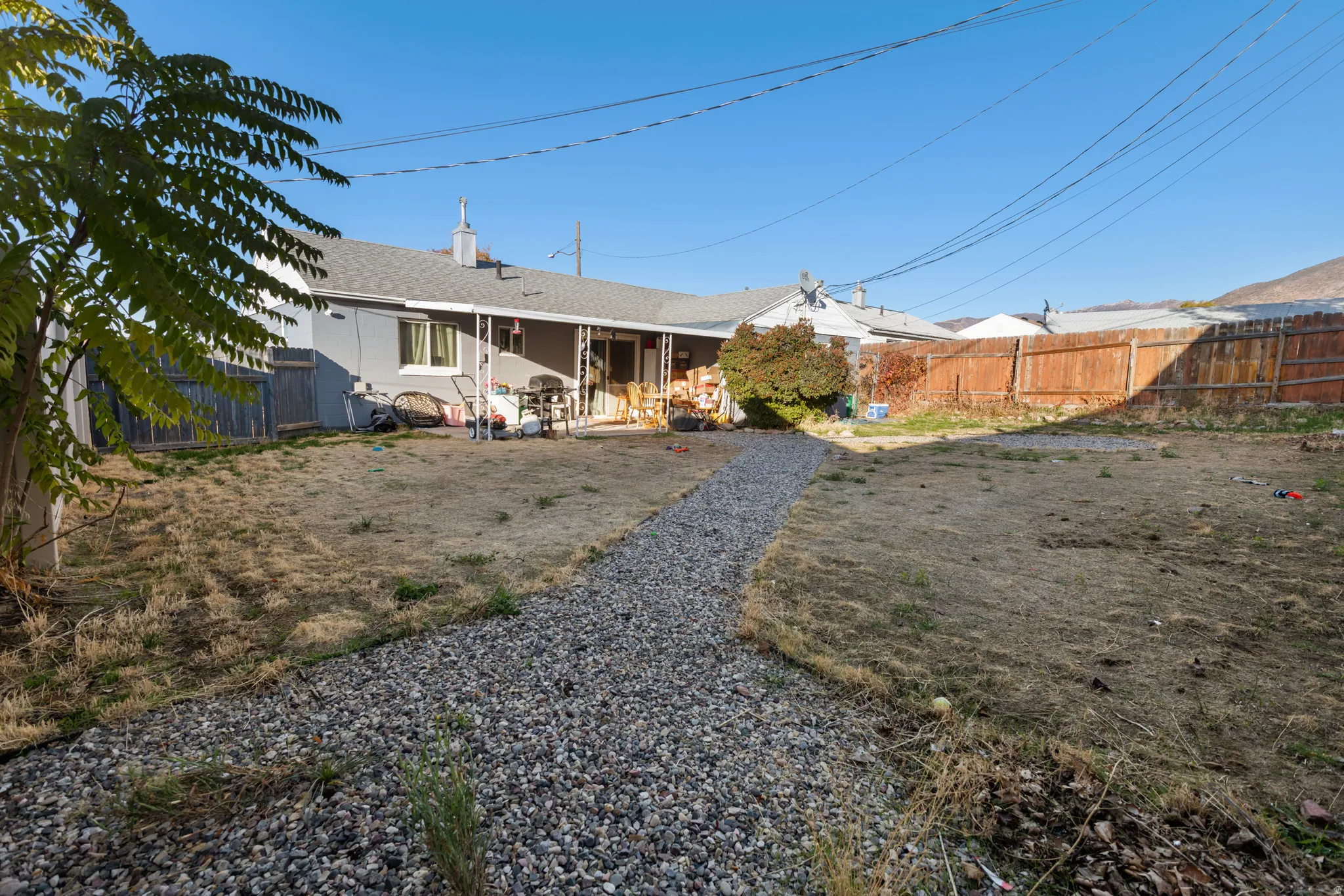 Rear view of house featuring a fenced backyard, a chimney, and roof with shingles