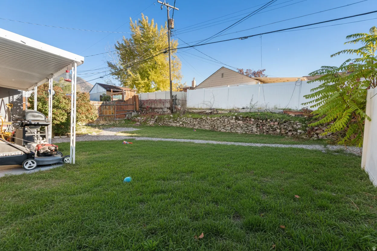 View of fenced backyard with AI-staged lawn
