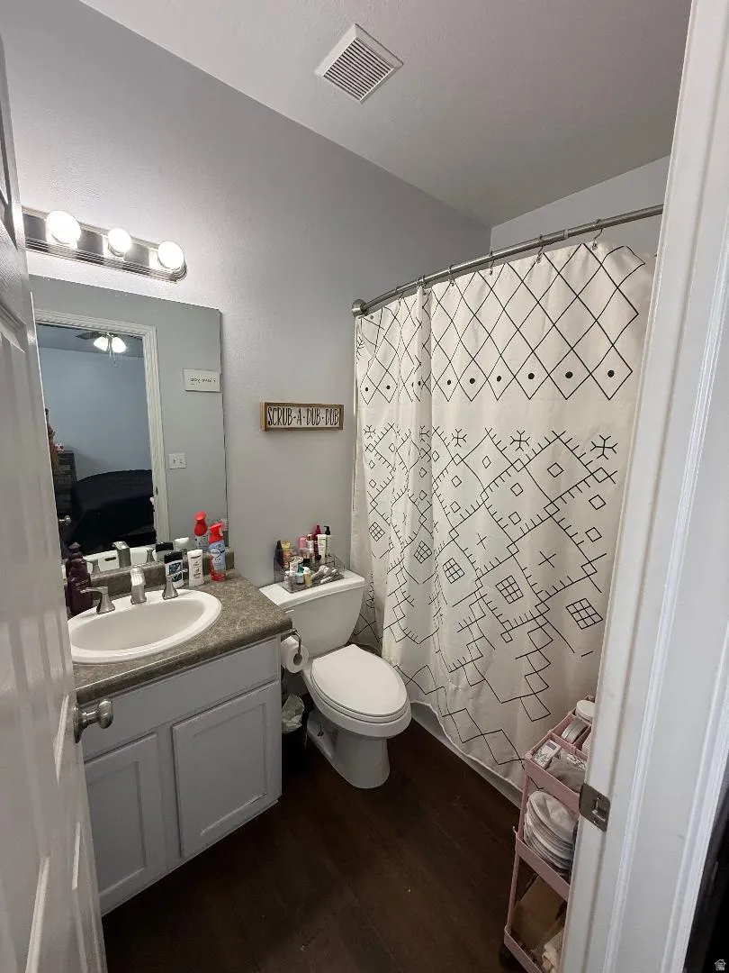 Ensuite bathroom with dark wood-style floors, vanity, and a shower with curtain