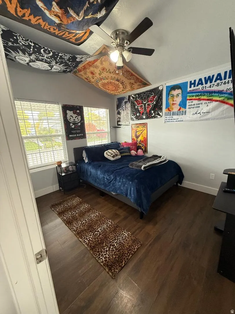 Bedroom with vaulted ceiling, dark wood-style flooring, and a ceiling fan