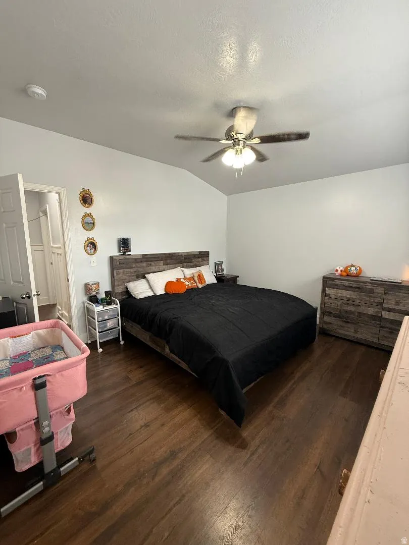 Bedroom with dark wood-style floors, a textured ceiling, lofted ceiling, and a ceiling fan