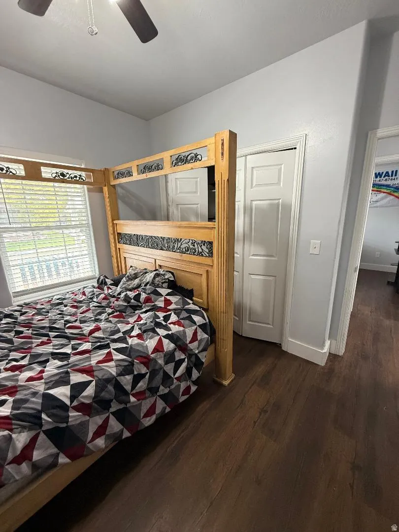 Bedroom featuring dark wood-style floors, ceiling fan, and a closet