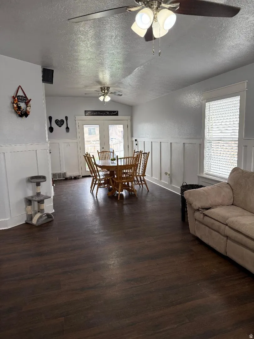 Dining area with a decorative wall, a wainscoted wall, dark wood finished floors, and a textured ceiling