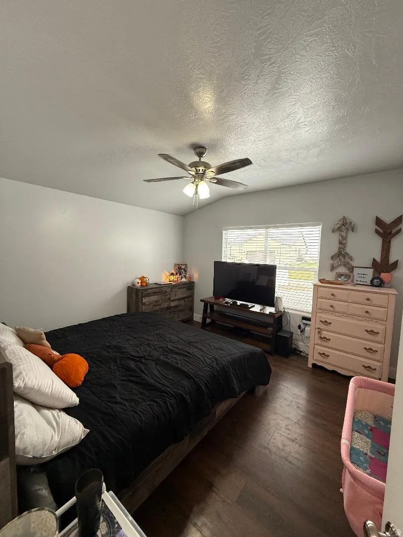 Bedroom featuring wood finished floors, a textured ceiling, ceiling fan, and lofted ceiling