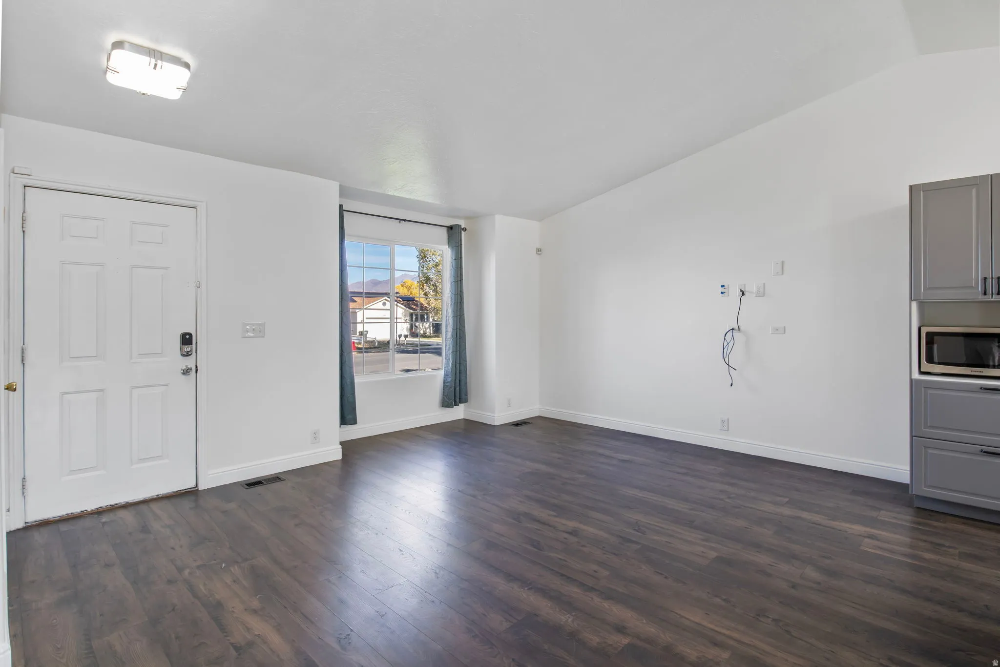 Foyer entrance with dark wood-style floors and lofted ceiling
