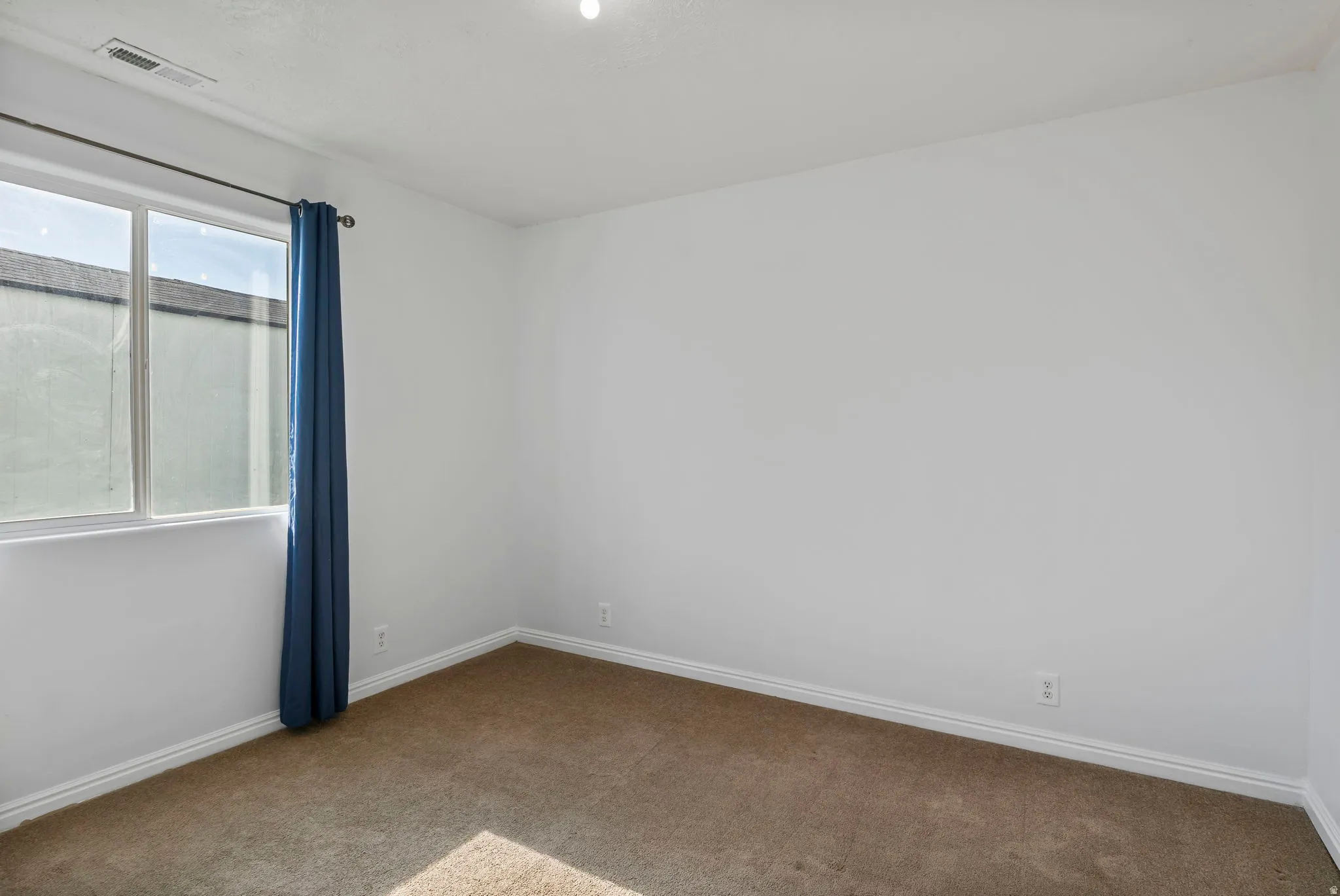 Carpeted spare room featuring baseboards
