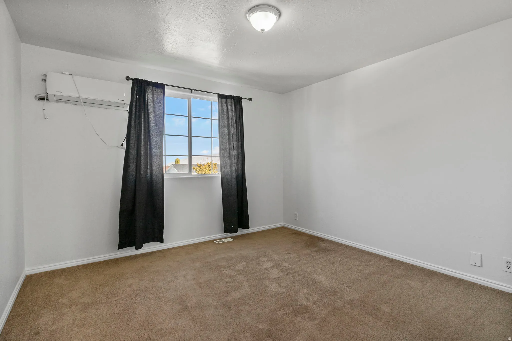 Master Bedroom room featuring light colored carpet, a wall unit AC, and a textured ceiling