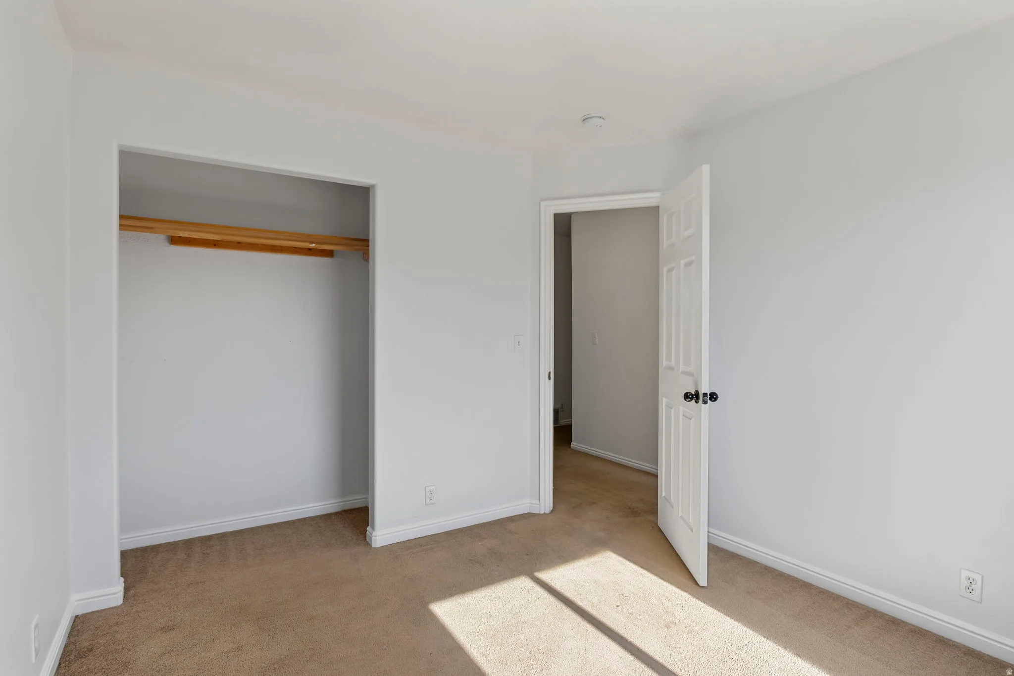 Unfurnished bedroom featuring light carpet and a closet