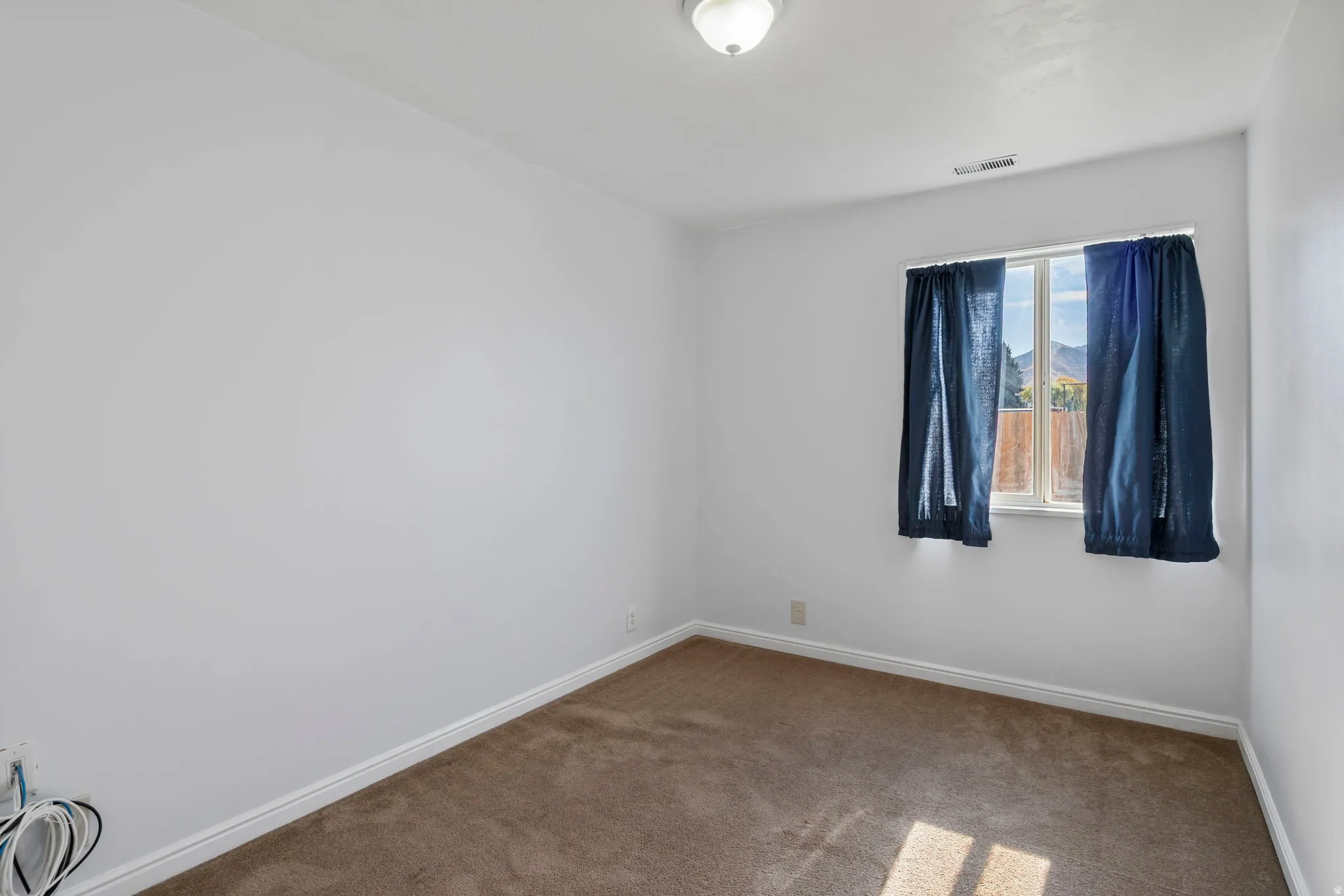 Carpeted spare room featuring baseboards