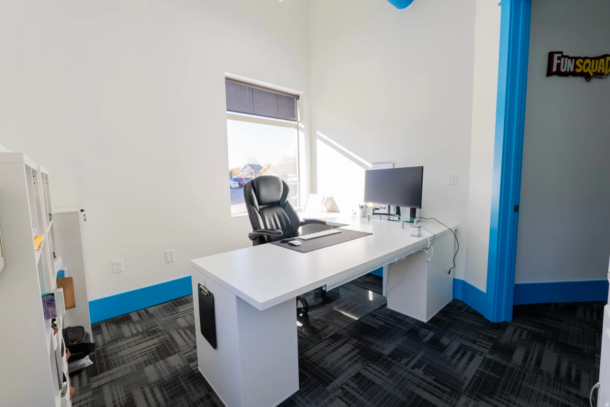 Office with dark colored carpet and a high ceiling
