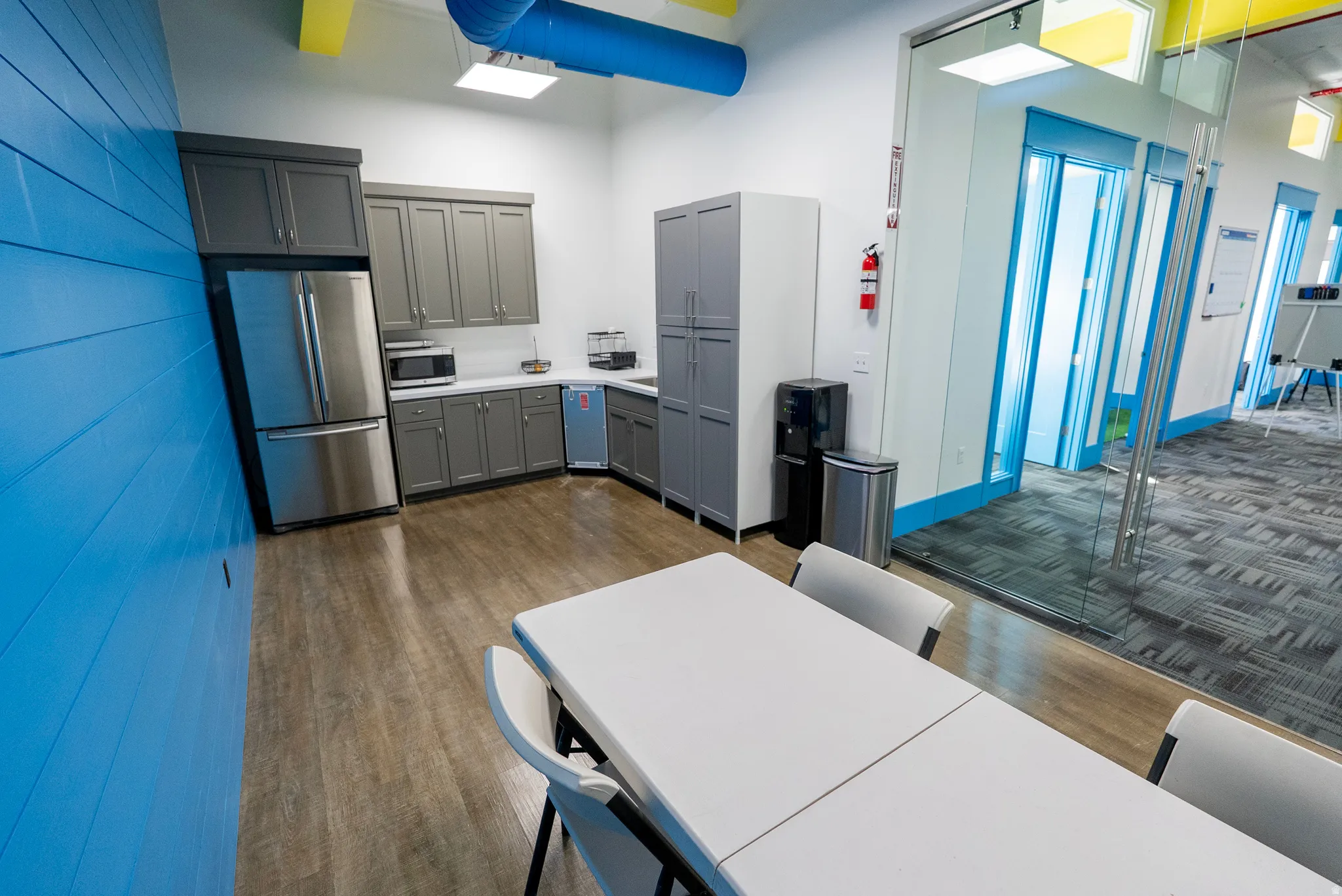 Kitchen featuring gray cabinets, appliances with stainless steel finishes, light countertops, dark wood finished floors, and a high ceiling