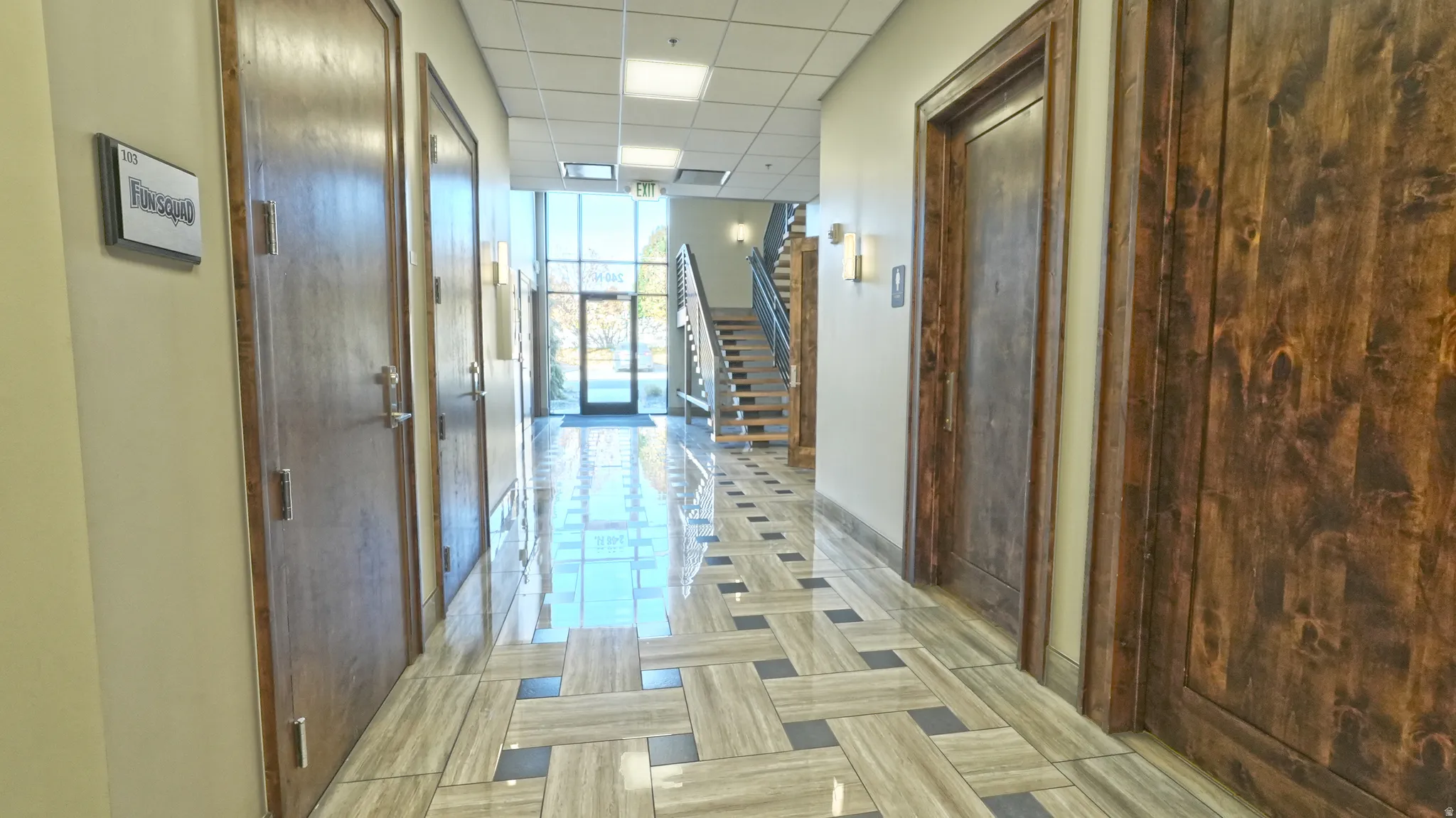 Hall with stairs, a drop ceiling, and a wall of windows
