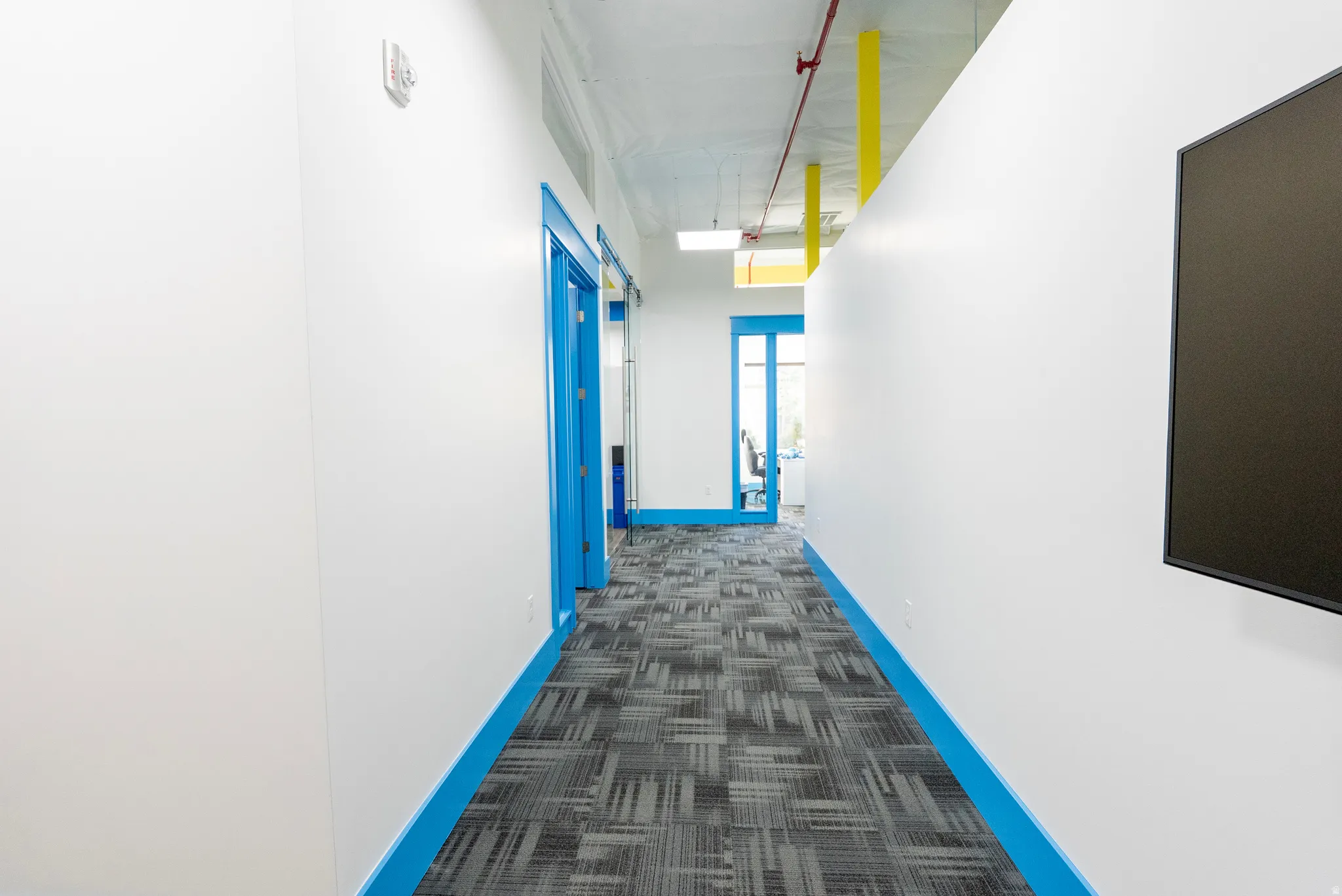 Hallway featuring dark colored carpet and baseboards