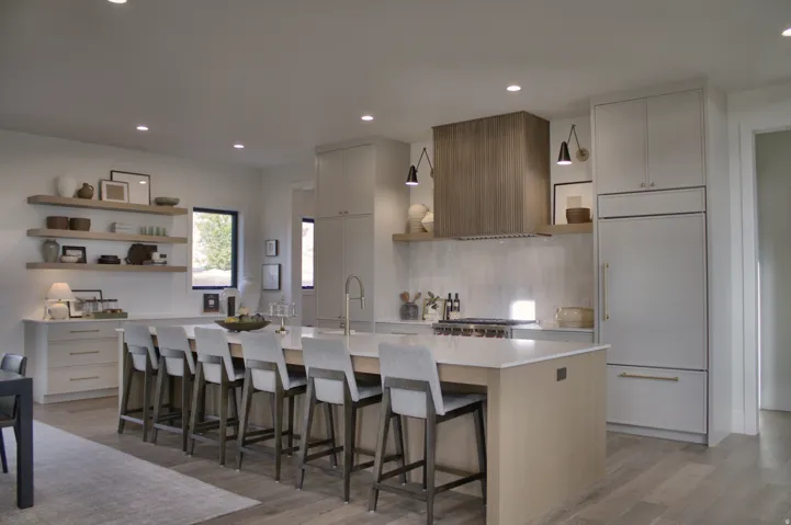 Spacious kitchen featuring a large central island, integrated appliances, wood-finish flooring, and open shelving