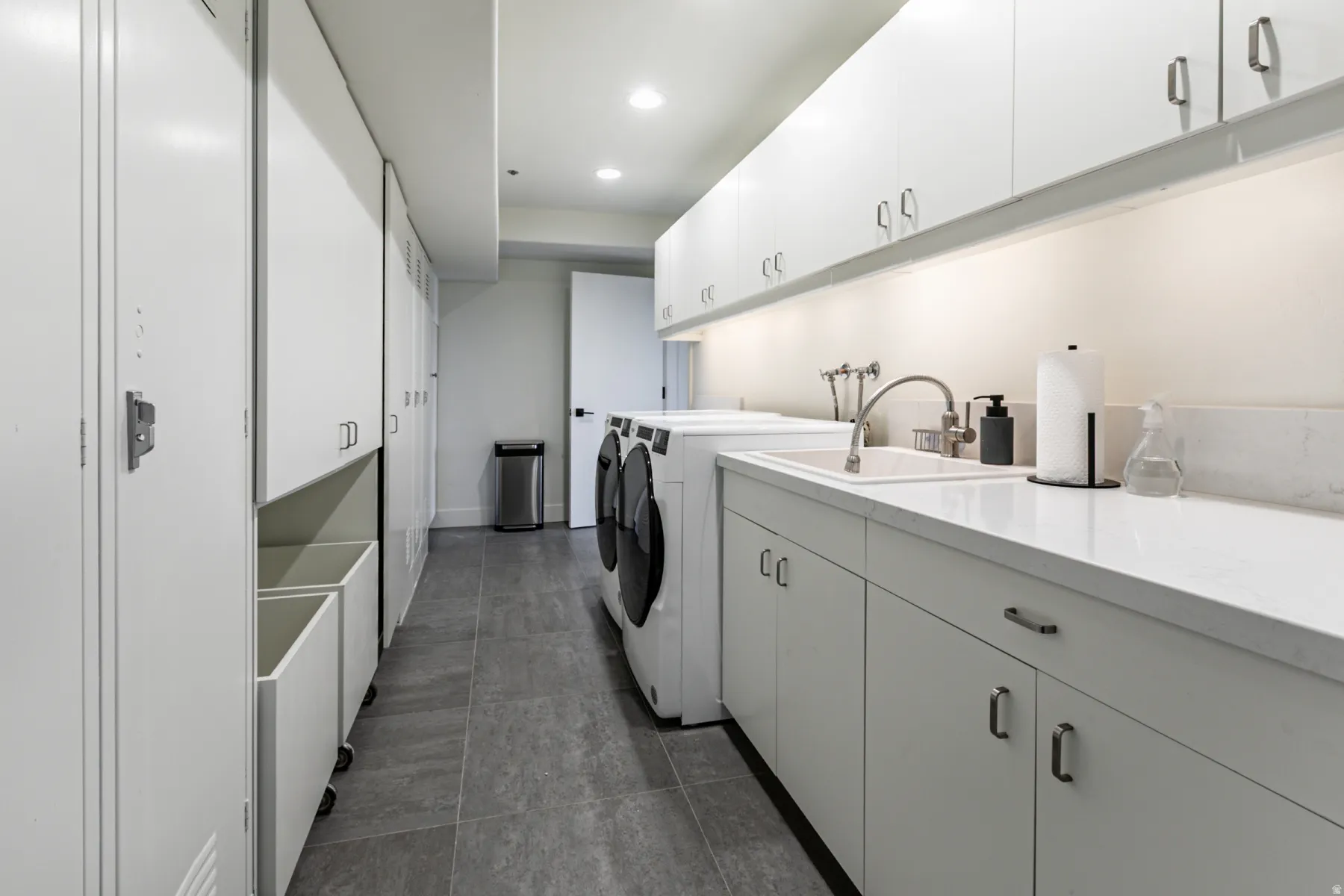 Laundry room featuring cabinet space, recessed lighting, washing machine and clothes dryer, and dark tile patterned floors