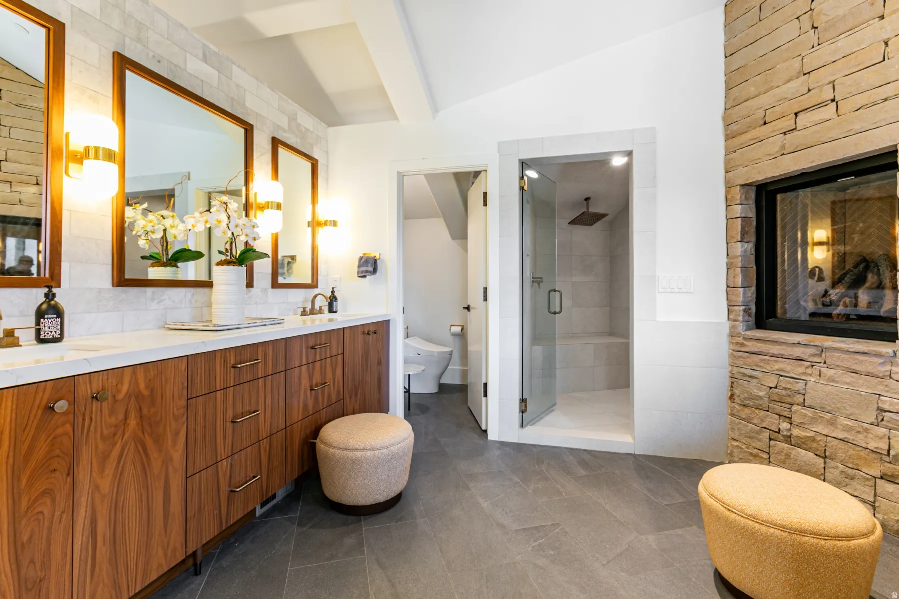 Bathroom featuring double vanity, a shower stall, and tasteful backsplash