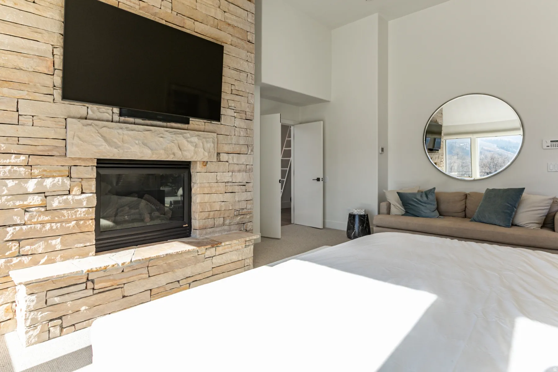 Carpeted bedroom with a high ceiling and a stone fireplace