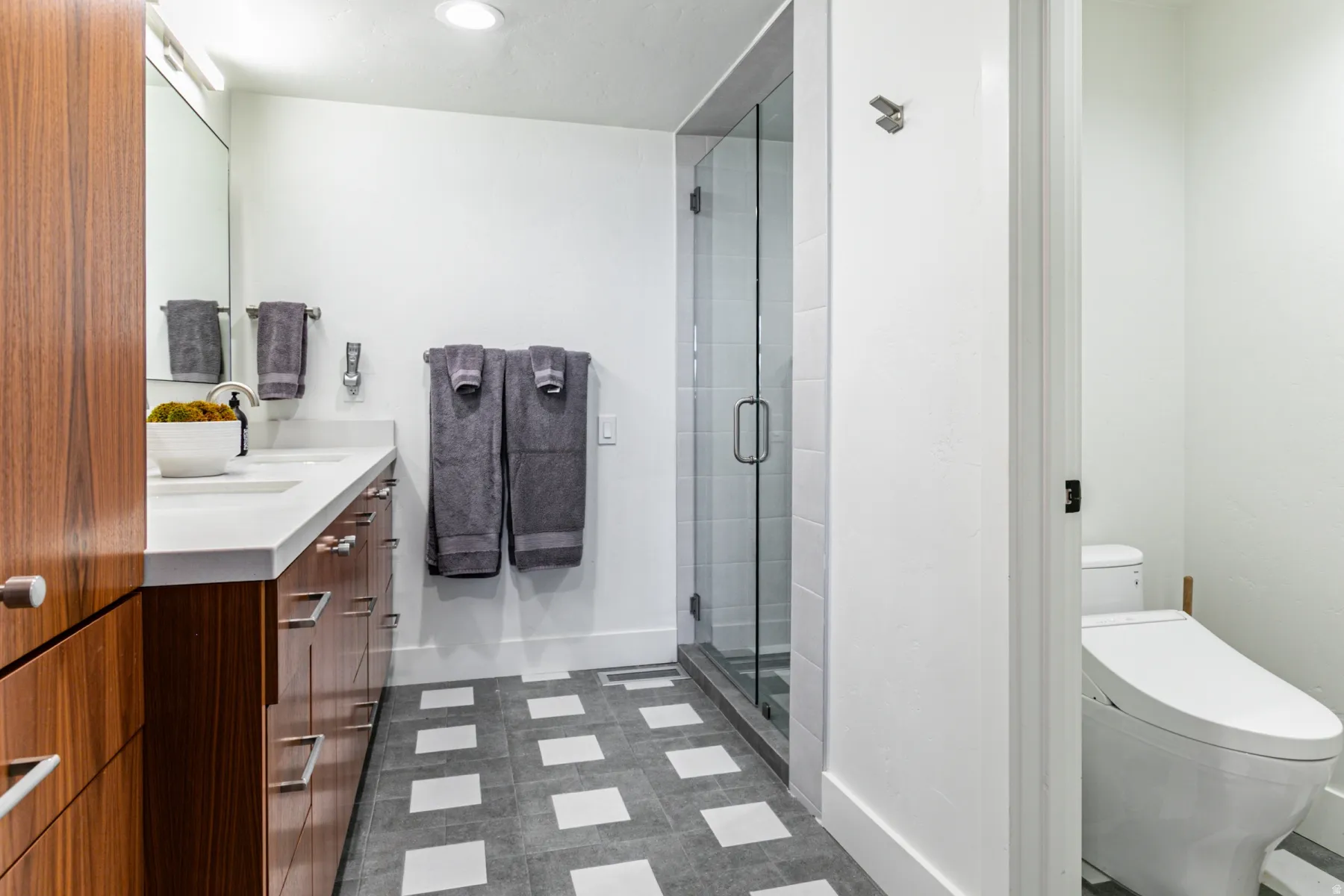 Full bath featuring double vanity, a stall shower, and dark floors