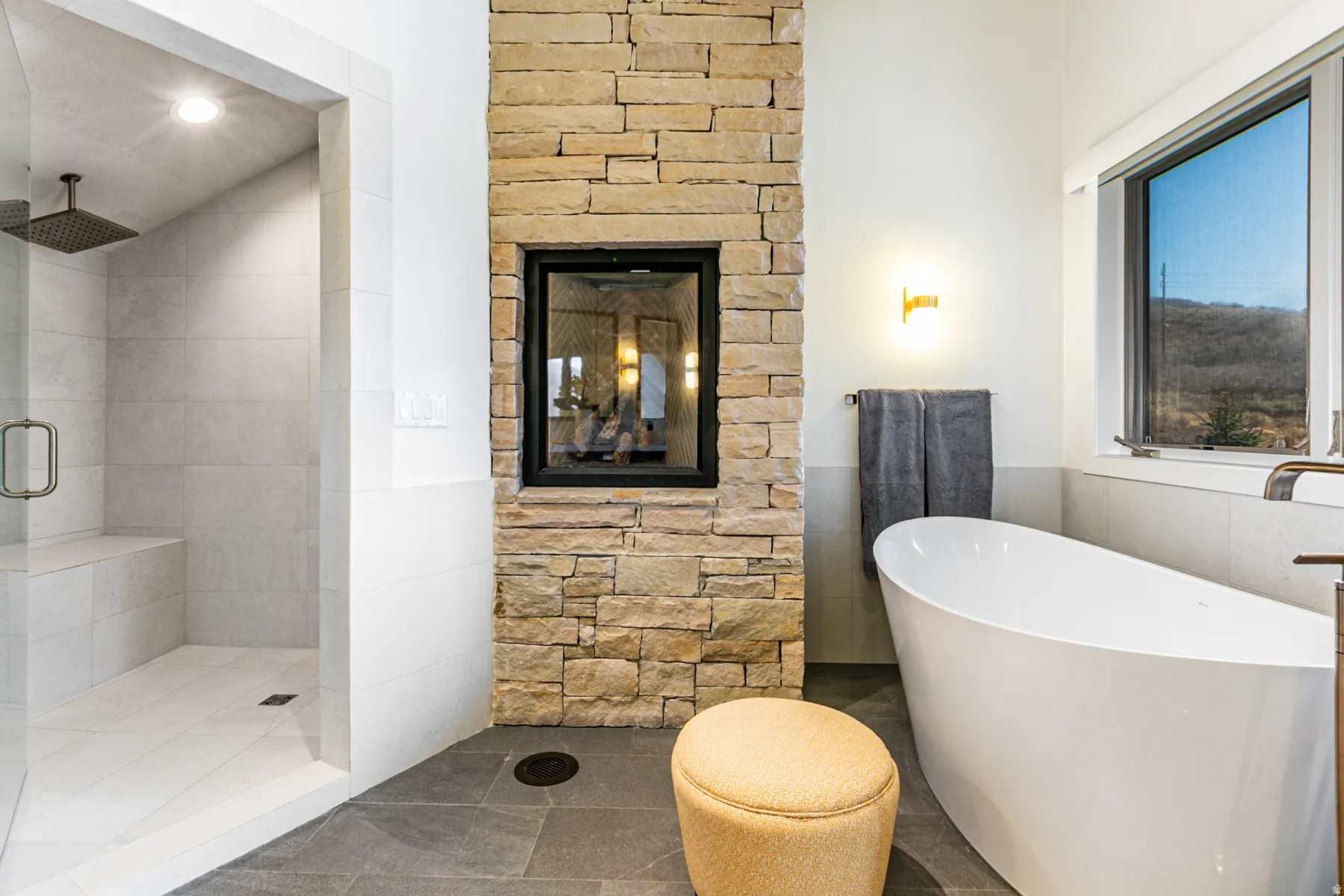 Bathroom featuring a freestanding bath, tile walls, a stall shower, a wainscoted wall, and tile patterned flooring