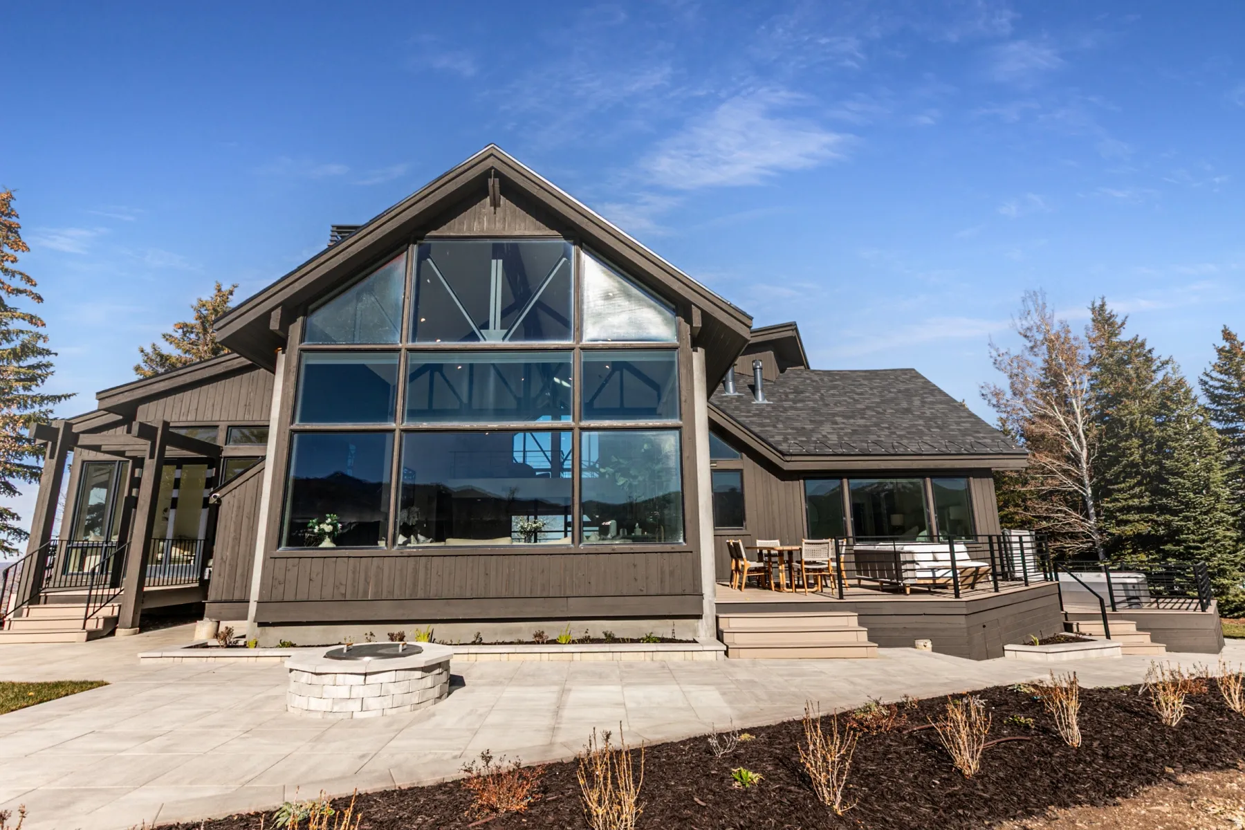 Rear view of house featuring an outdoor fire pit, a patio, a sunroom, and a wooden deck