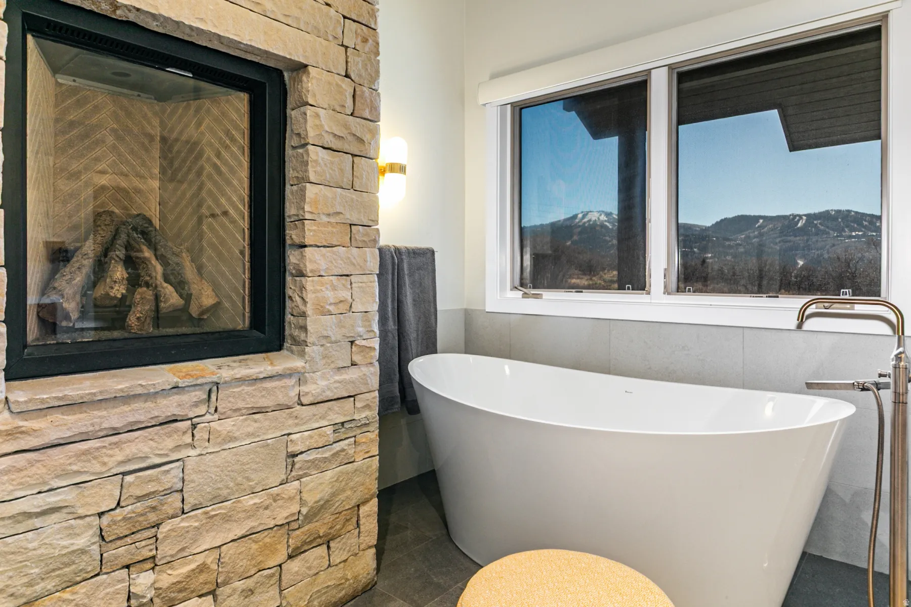 Full bath featuring a freestanding bath, a mountain view, a wainscoted wall, and tile walls
