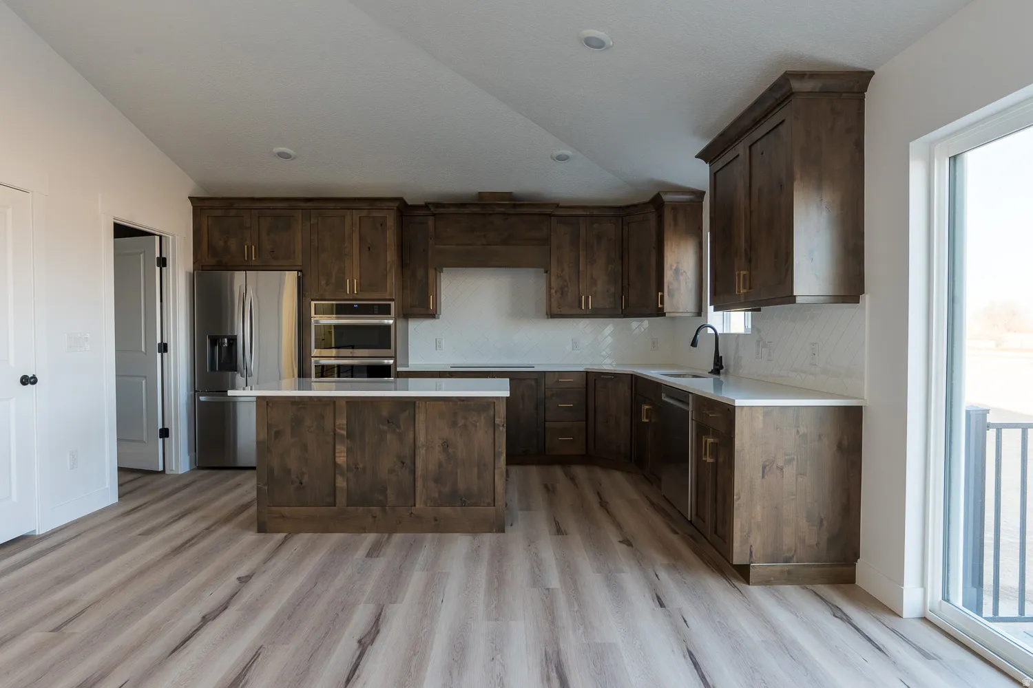 Kitchen with dark brown cabinets, stainless steel appliances, healthy amount of natural light, a center island, and lofted ceiling