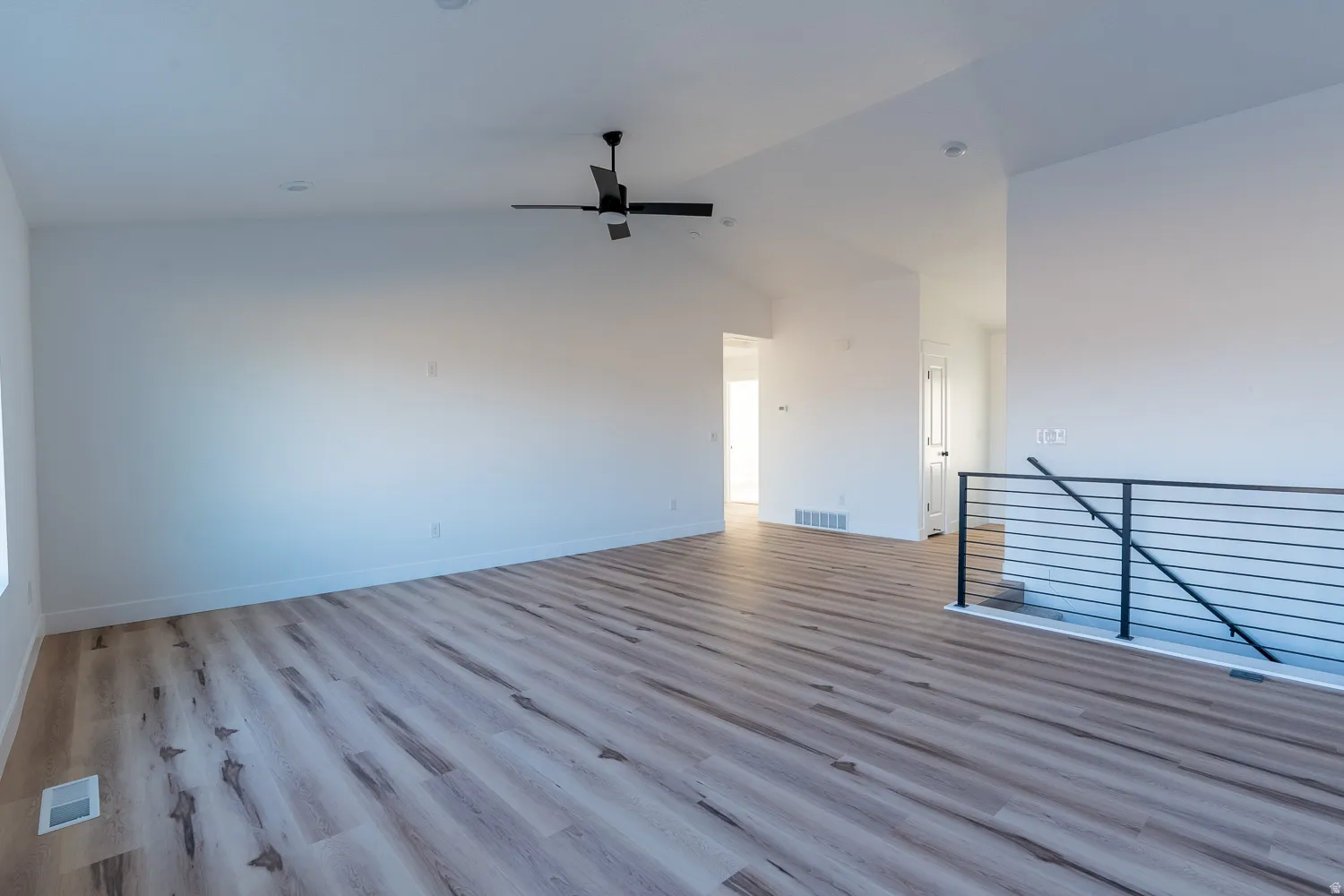 Empty room featuring lofted ceiling, light wood-type flooring, and ceiling fan