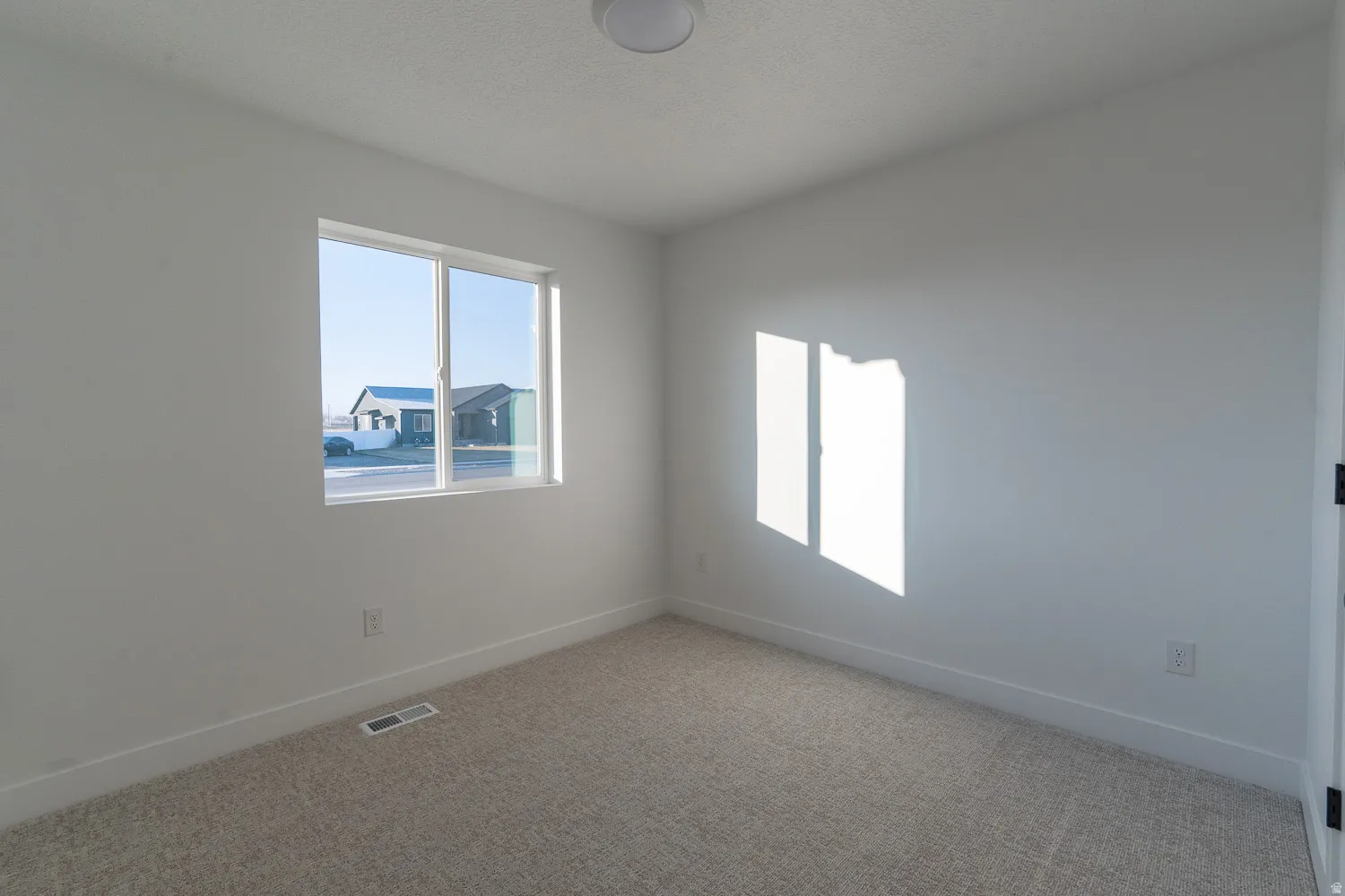 Carpeted spare room featuring baseboards