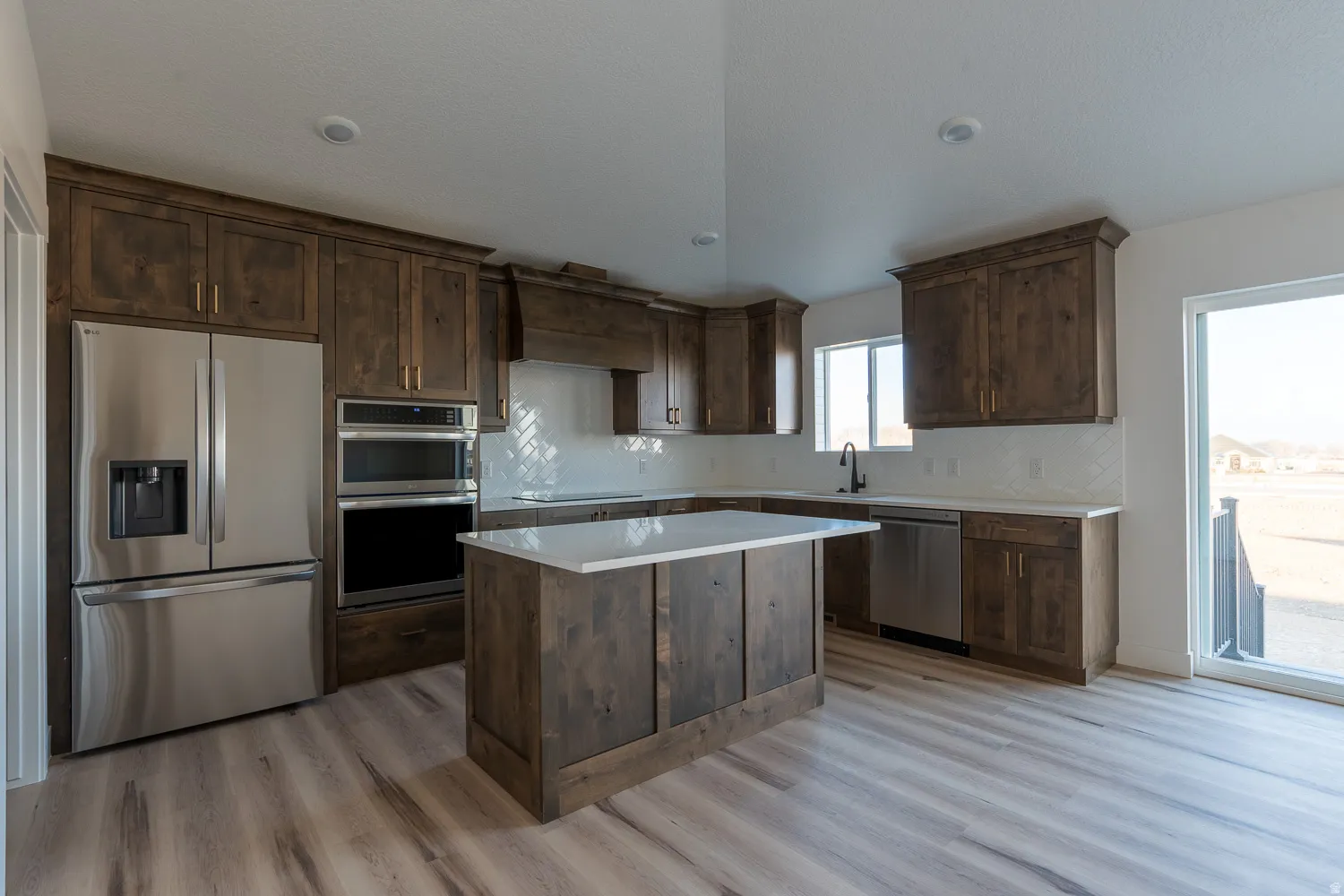 Kitchen with dark brown cabinetry, stainless steel appliances, tasteful backsplash, a kitchen island, and premium range hood