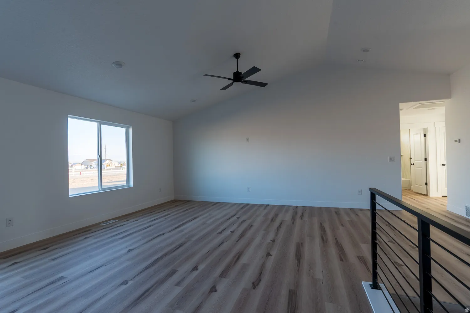 Empty room featuring vaulted ceiling, light wood-style floors, and ceiling fan