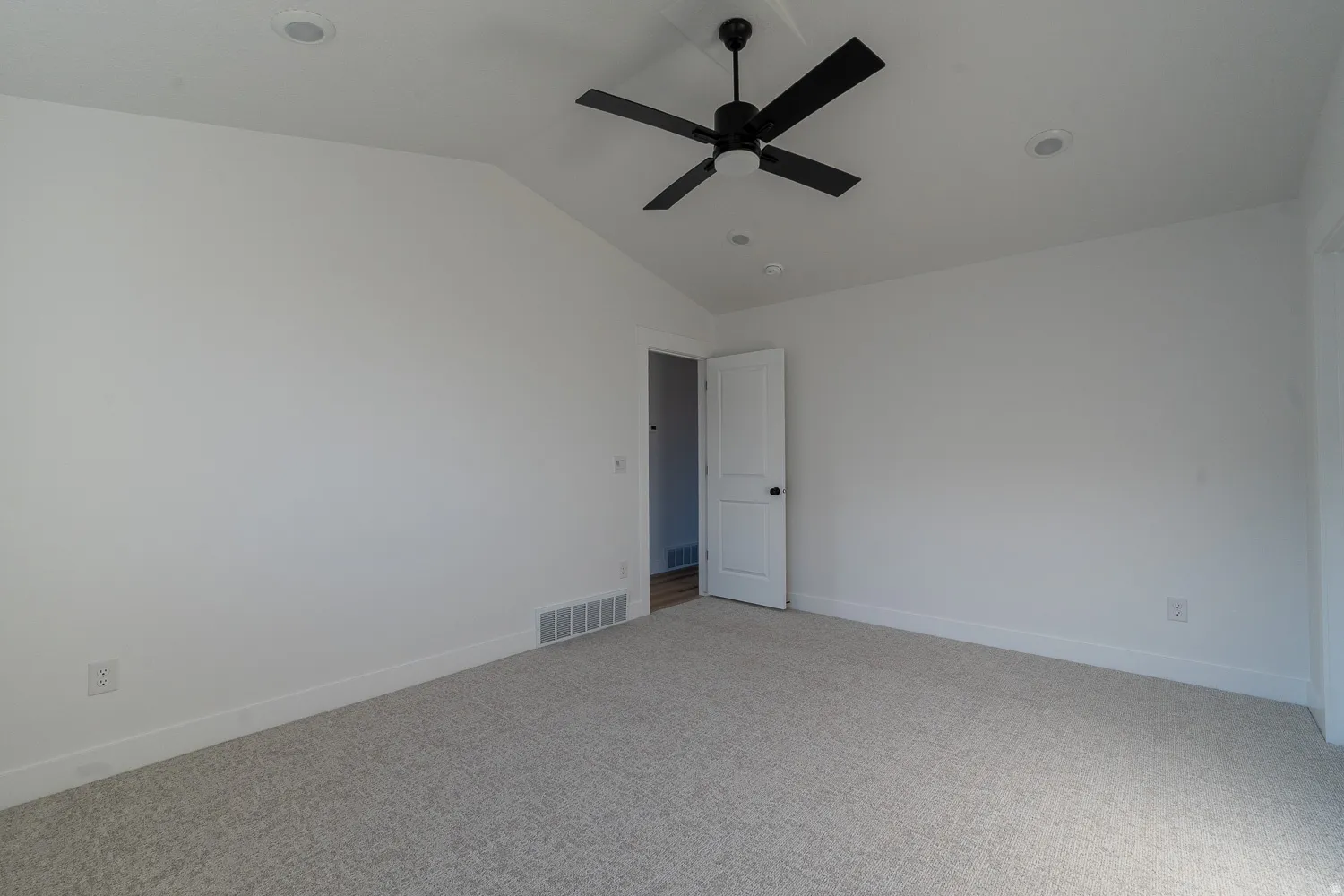 Carpeted spare room with vaulted ceiling and a ceiling fan