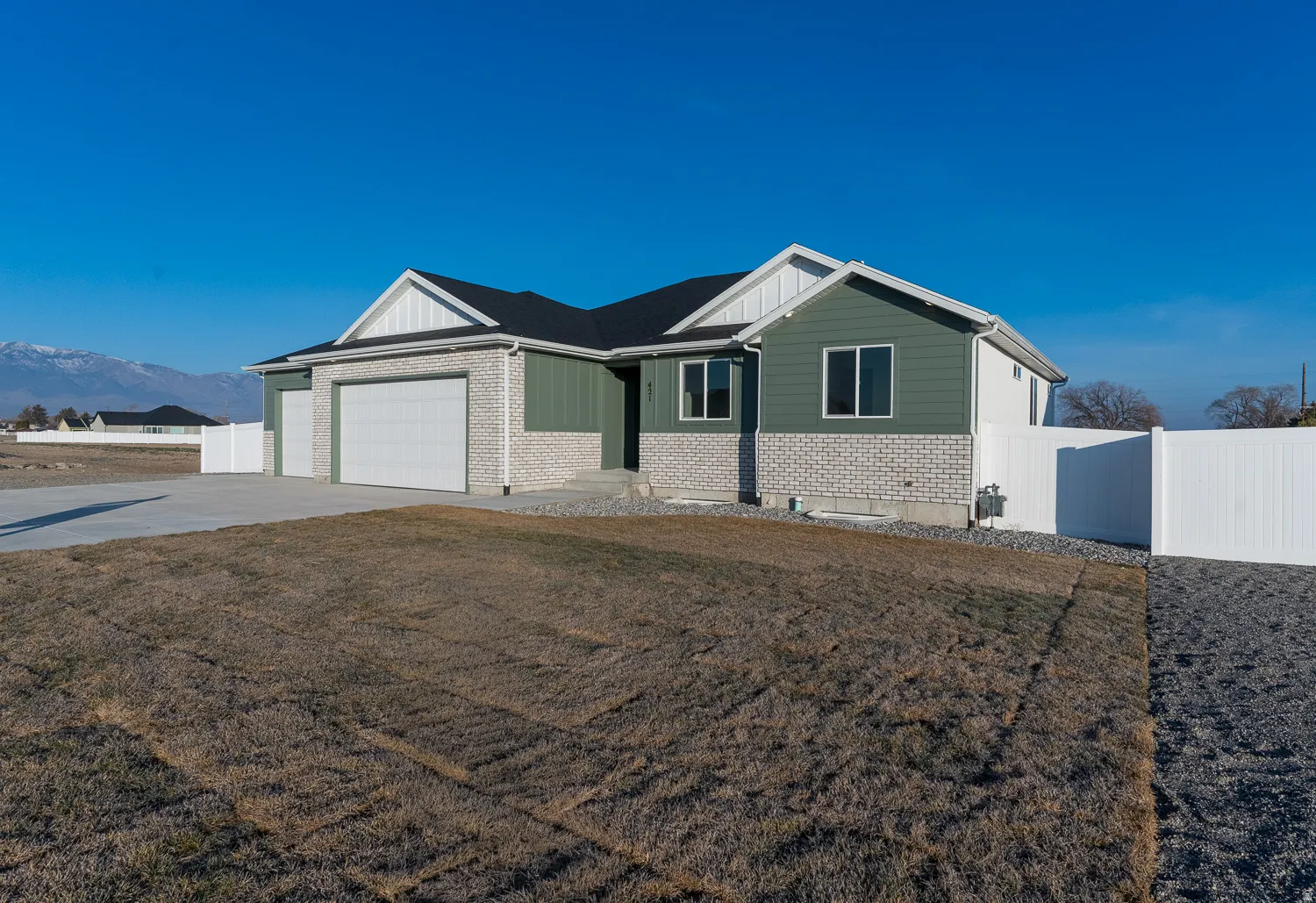 View of front of home featuring brick siding, a garage, driveway, and board and batten siding