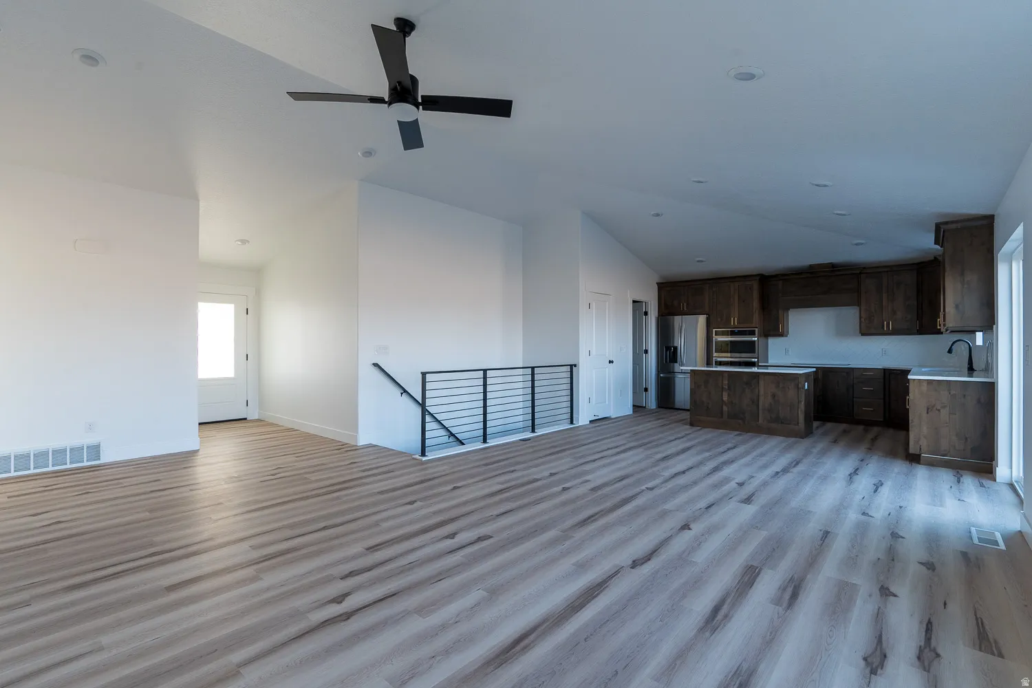 Unfurnished living room with light wood-type flooring, a ceiling fan, and high vaulted ceiling