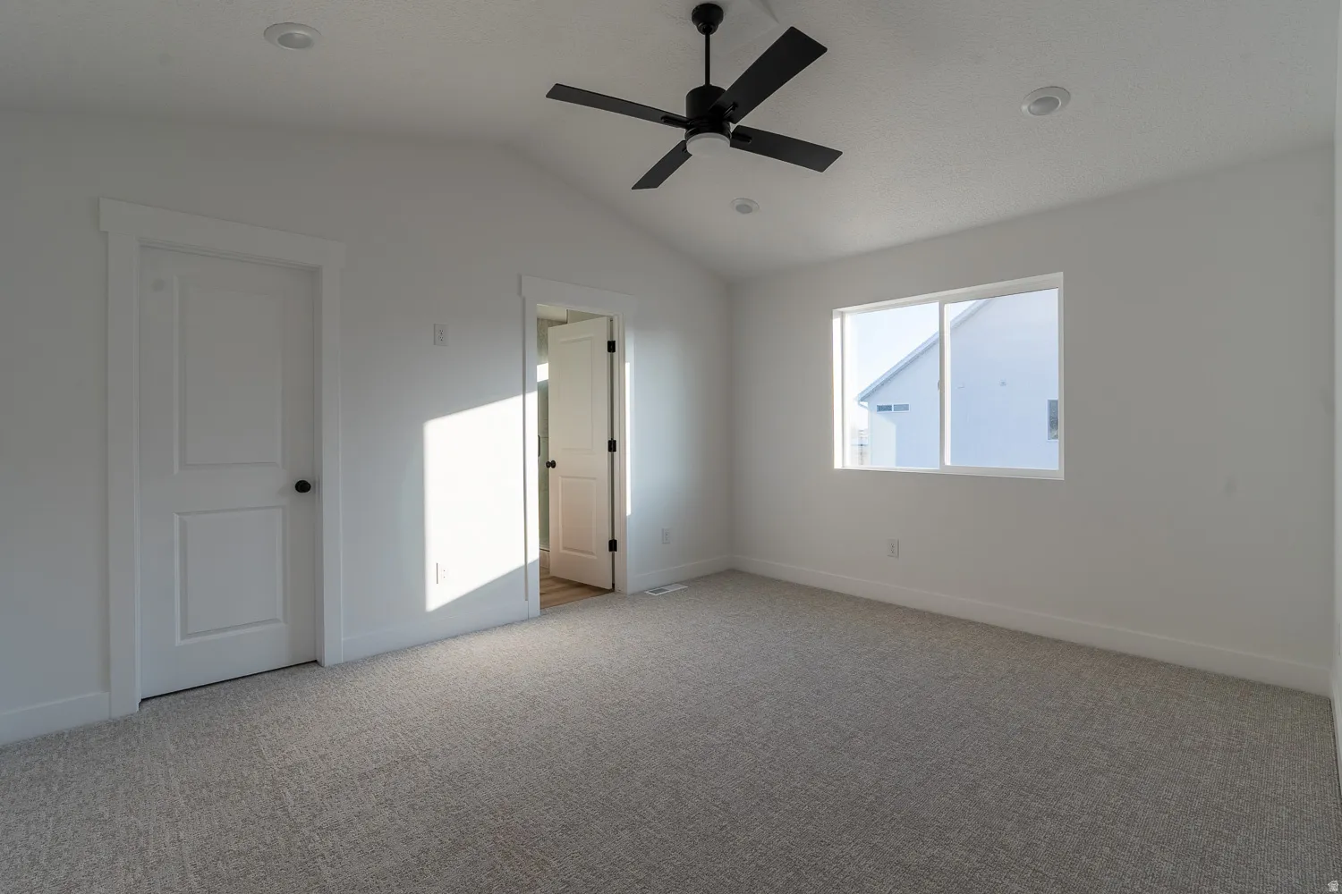 Unfurnished bedroom featuring vaulted ceiling, light colored carpet, and a ceiling fan