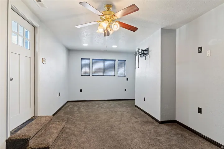 Unfurnished room featuring carpet, ceiling fan, and a textured ceiling