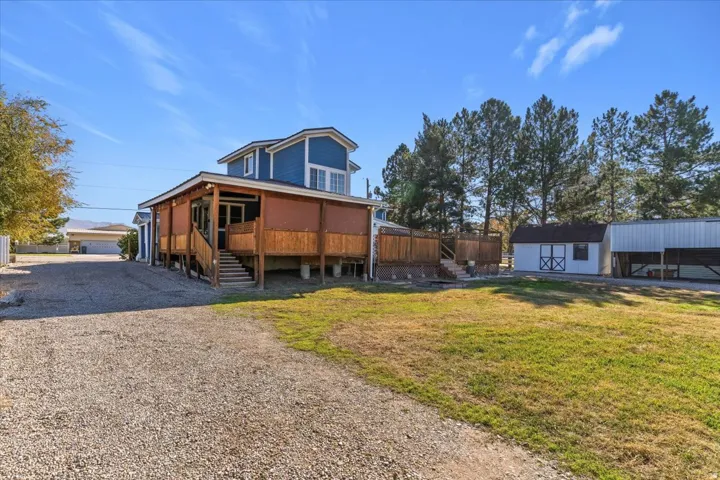 Back of property featuring an outdoor structure, a yard, stairs, and a deck