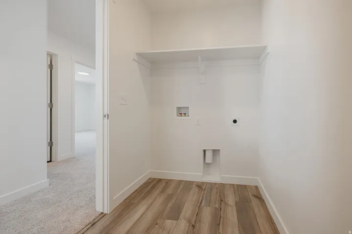 Dedicated laundry alcove featuring wood-finish flooring, a built-in shelf, and utility hookups