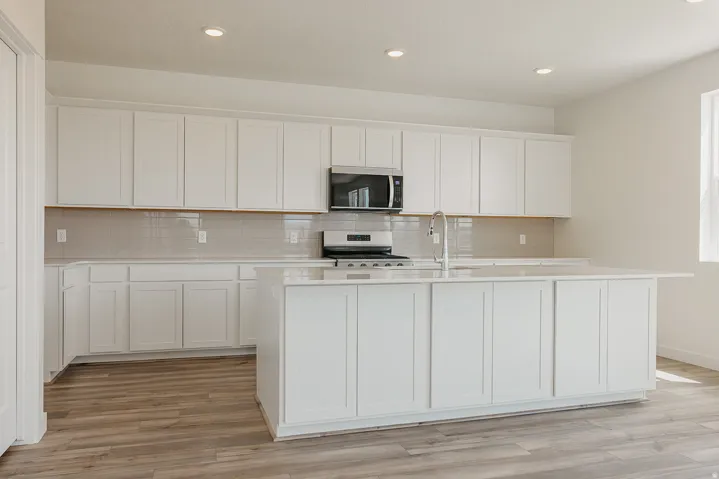 Kitchen featuring an expansive island, white cabinetry, stainless steel appliances, and wood-finish flooring