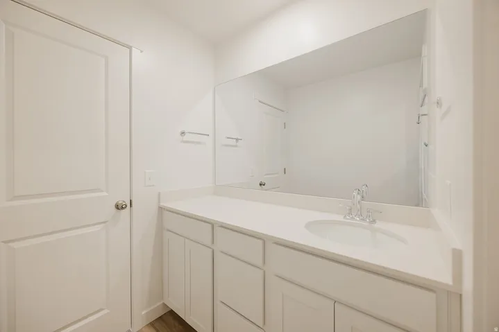 White shaker-style cabinetry with a countertop, undermount sink, and chrome faucet