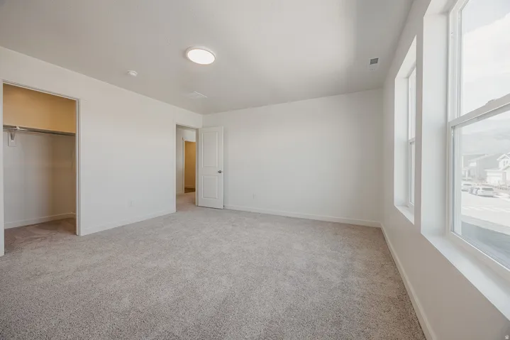 Neutral paint palette, recessed lighting, double-hung windows, carpeted flooring, and built-in closet with hanging rod