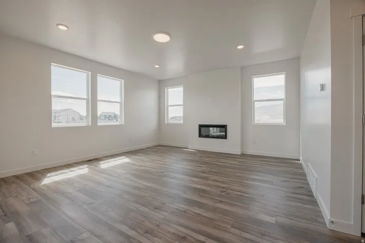 Wood-finish flooring, recessed lighting, multiple windows, built-in fireplace, and a light color palette