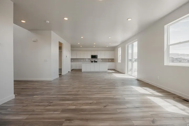 Expansive open-concept space featuring wood-finish flooring, recessed lighting, and large windows