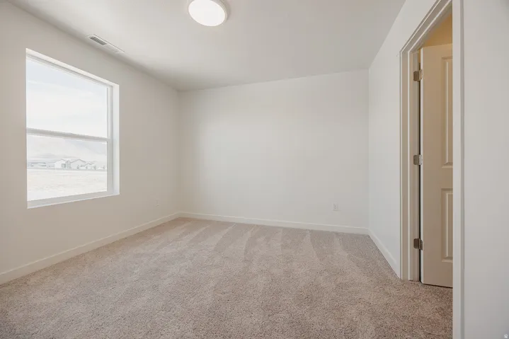 Neutral carpeting, white painted walls, and a single window with a white frame