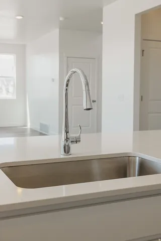 Single-basin sink with a chrome gooseneck faucet, integrated into a light-toned countertop