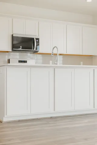 White shaker-style cabinetry with a stainless steel microwave and a pull-down faucet