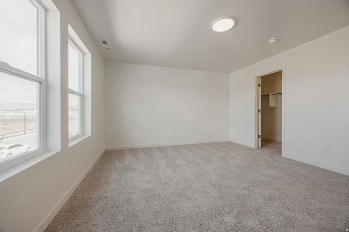 Neutral-toned carpeting, white walls, and bright overhead lighting
