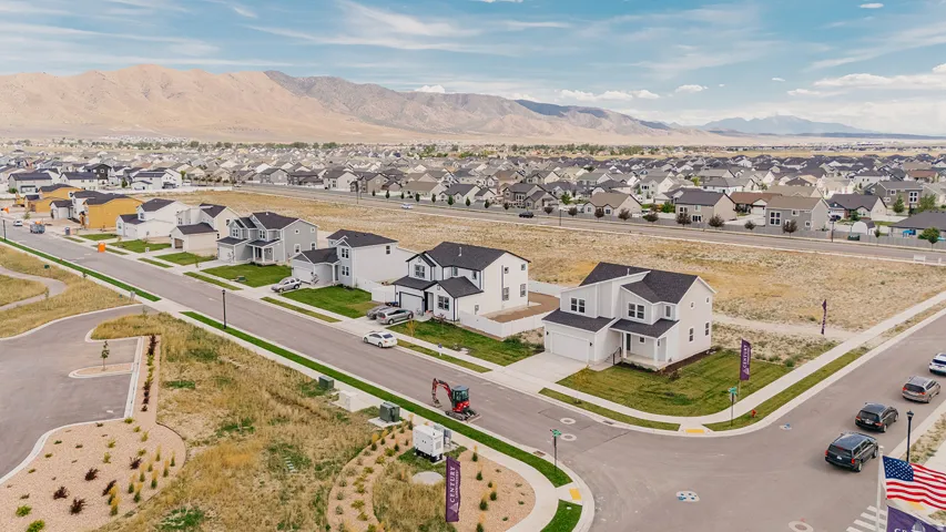 New construction homes with varied architectural styles, a paved street, and landscaped park strips