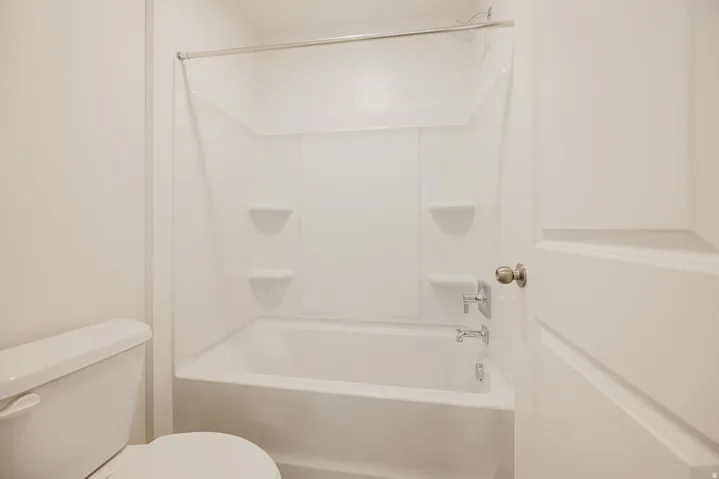 White bathtub and shower combination with integrated shelving